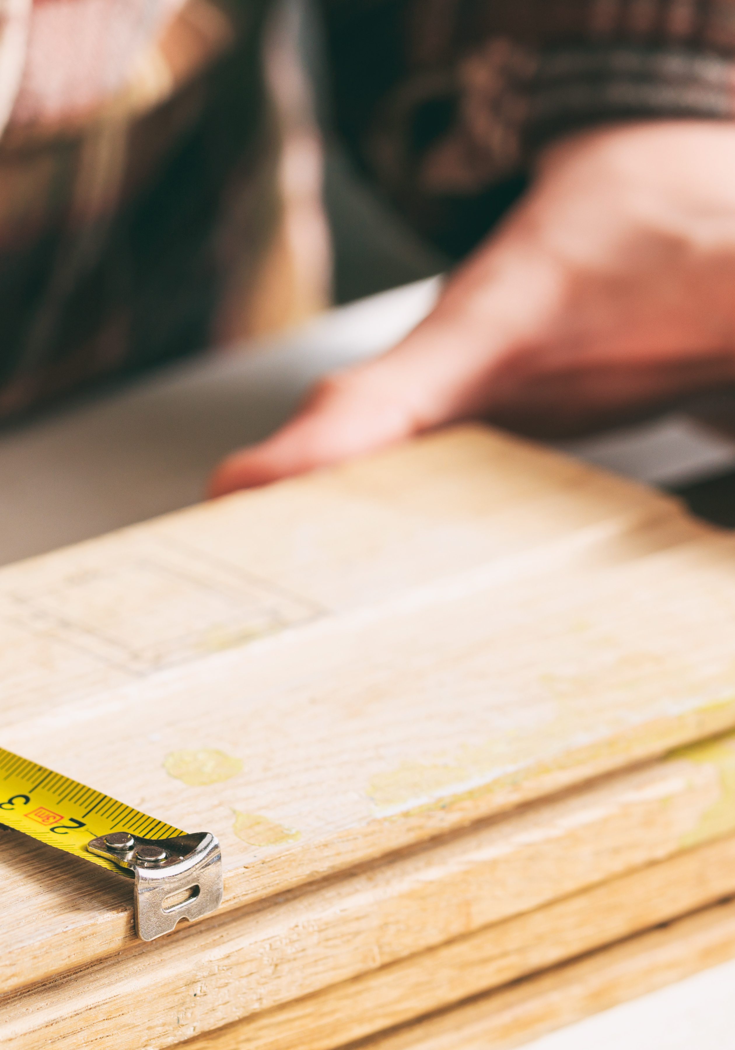 Carpenter holding a measure tape on the work bench