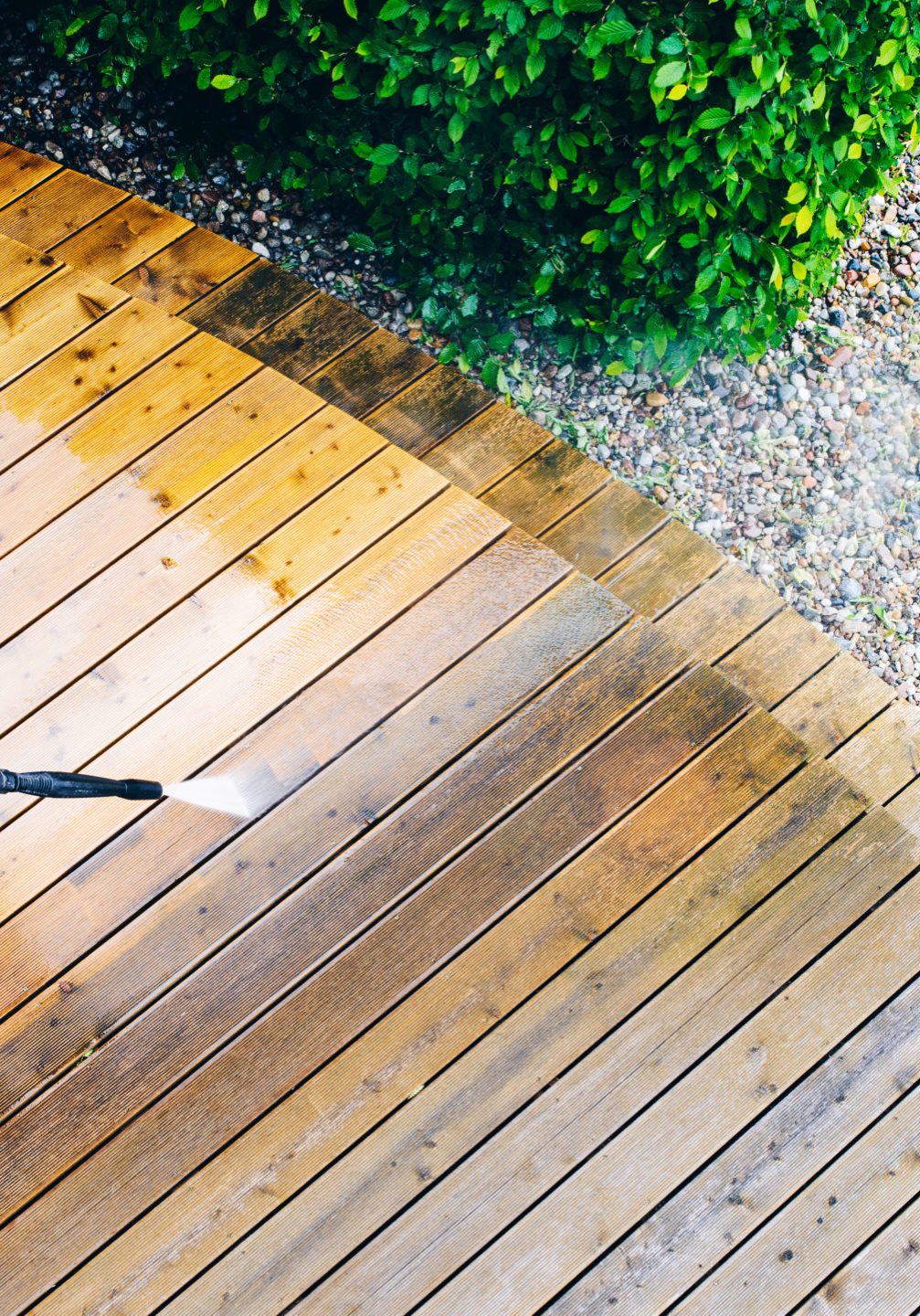 man cleaning terrace with a power washer - high water pressure cleaner on wooden terrace surface