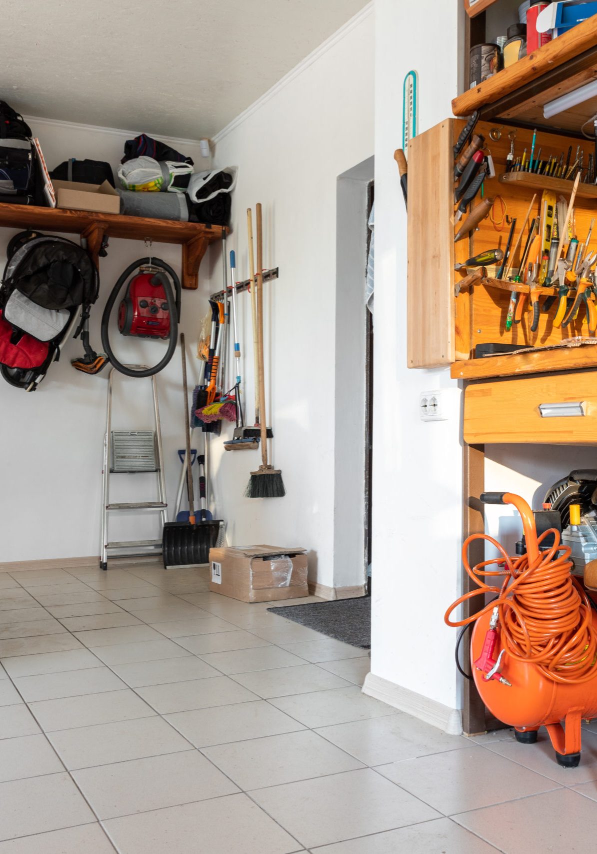 Home suburban car garage interior with wooden shelf, tools equipment stuff storage warehouse on white wall indoor. Vehicle parked at house parking background. DIY workbench for repair home appliances.